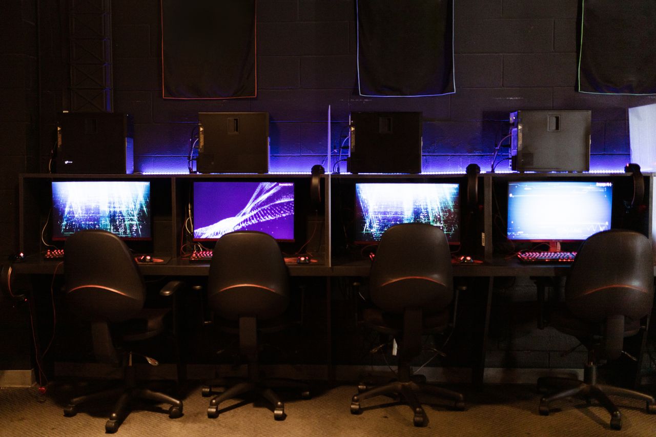 Services A modern gaming setup with multiple computers and LED lighting, perfect for e-sports and gaming environments.