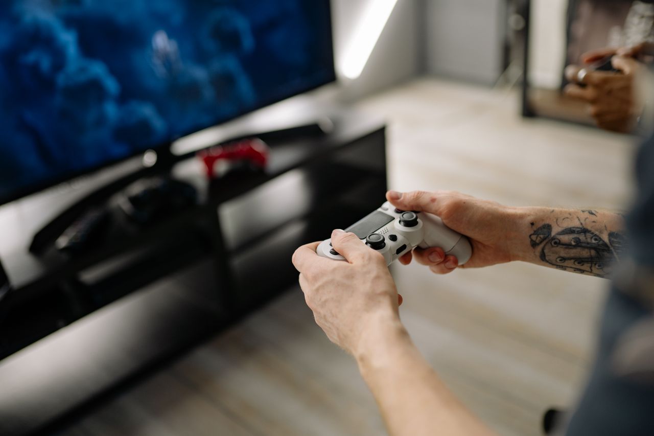 Services Person playing video games using a game controller indoors on a modern TV setup.